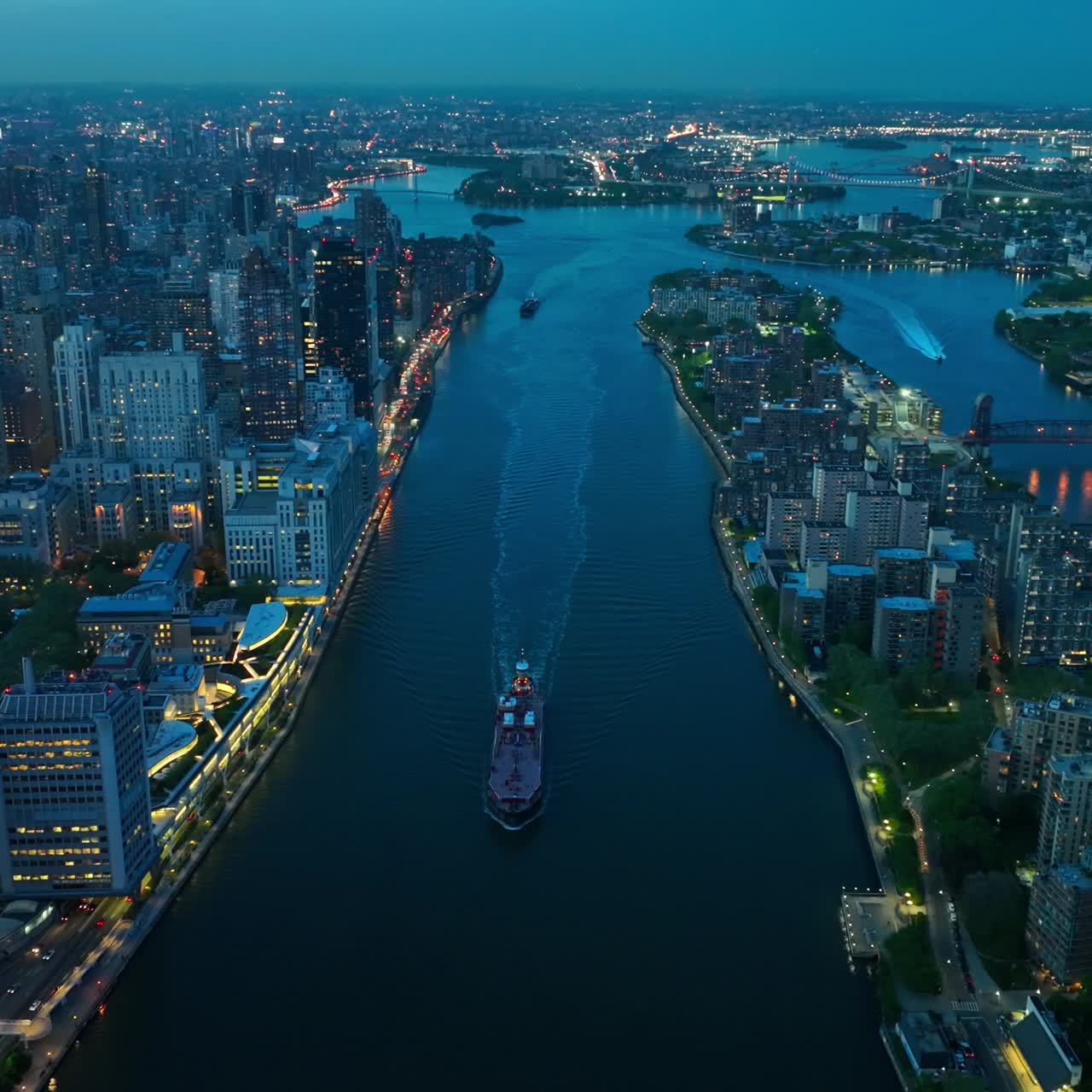 Boats moving by the calm river in beautiful New York. Evening time with lights on in fantastic metropolis. Top view