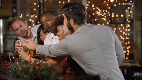 amigos haciendo un brindis en una fiesta de navidad en un bar