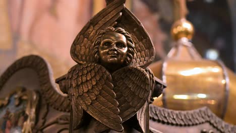 the detailed face and feathered wings of a cherub sculpture, a piece of sacred art within st. volodymyr's cathedral in kyiv, ukraine. this macro shot highlights the masterful carving of the ornament.