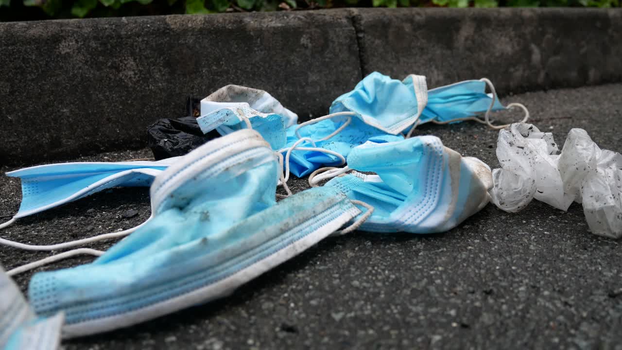 더럽게 버려진 사용된 코로나 바이러스 마스크는 바람에 쓰레기를 불고 거리 보도 근접 촬영 느린 돌리 오른쪽