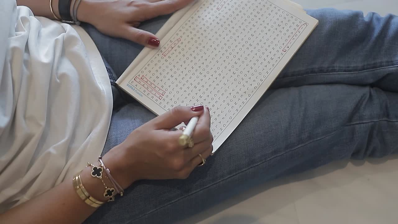 mujer joven sentada en casa resolviendo sopa de letras