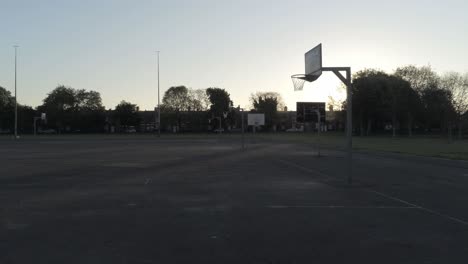 sunrise shadow silhouette empty basketball court dolly low right passing net
