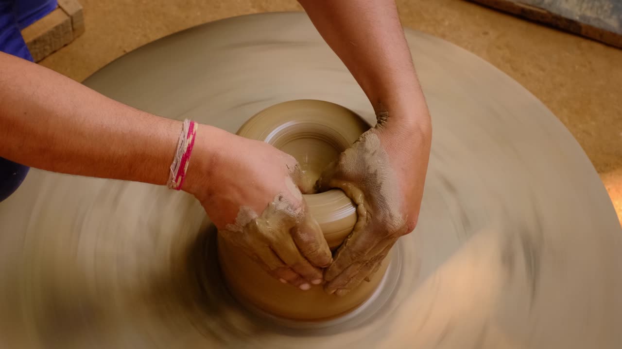 Pottery - skilled wet hands of potter shaping the clay on potter wheel. Pot, vase throwing. Manufacturing traditional handicraft Indian bowl, jar, pot, jug. Shilpagram, Udaipur, Rajasthan, India