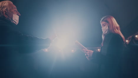 actors in masks quarreling on stage couple in medical masks arguing with each near near elderly man while rehearsing quarrel scene on stage in theater during pandemic