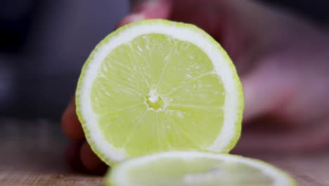 lemon being sliced with a knife on a wooden chopping board