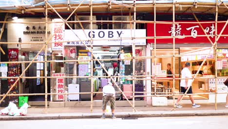 workers repairing storefront under bamboo scaffolding