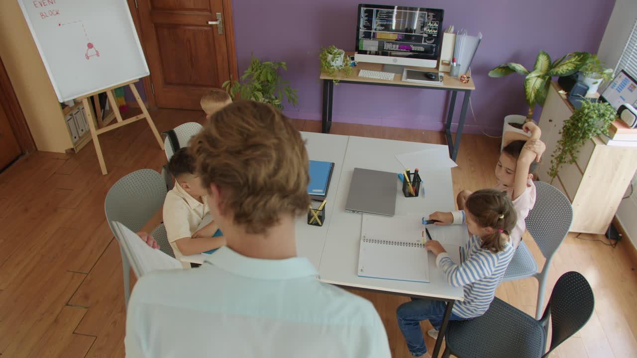 Teacher Holding Folder with Lesson Plan, Explaining Topic to Kids at IT Class