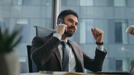 rich business owner calling phone rejoicing success sitting office close up.