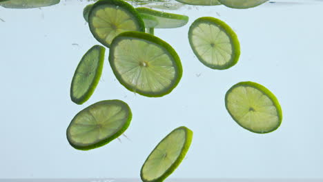 fresh lime submerged water on white background close up. citrus deep underwater.