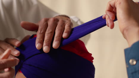 close up studio shot of two sikh men tying fabric for turban against plain background 2