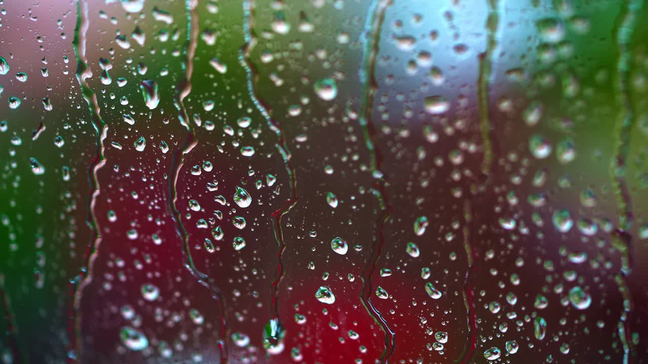 Rainy background on glass. Raindrops on window on blur background of bright dots. Drops of rain flow down the window. Drops of water drops on window pane.
