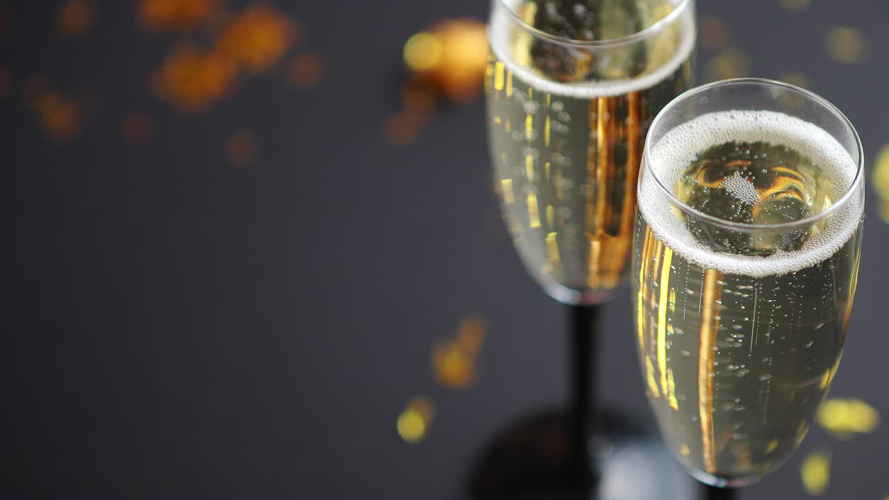 Due calici pieni di spumante champagne con decorazioni dorate.