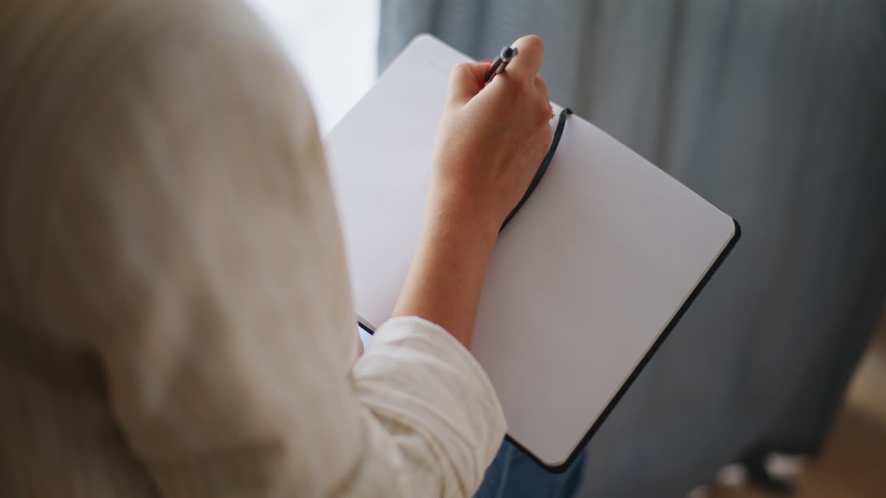 Close-Up of Businesswoman's Hands Writing in Notebook