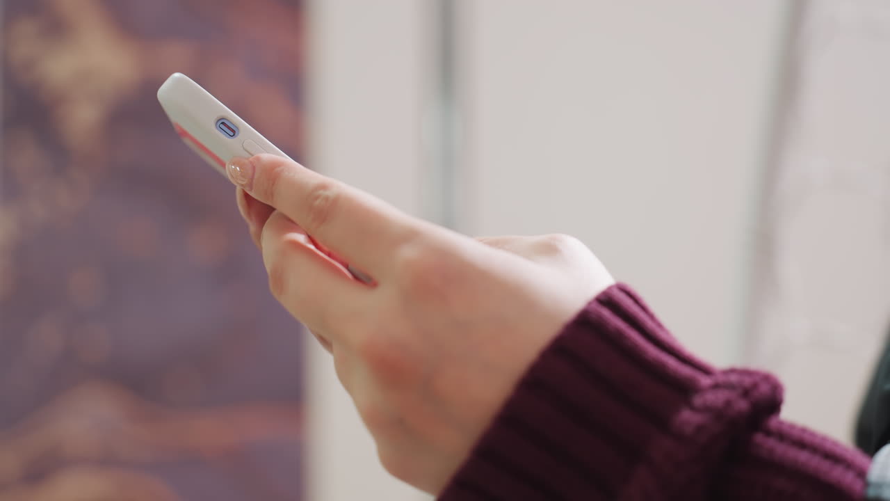 미용실에서 작은 리모컨을 들고 있는 손, 흰색 옷을 입은 고객 또는 스타일리스트가 집중된 손짓으로 타이머와 설정을 조정하고 있어요. 버튼과 디스플레이의 클로즈업이며 스웨터 소매가 보이고, 배경은 부드럽게 처리되었어요.