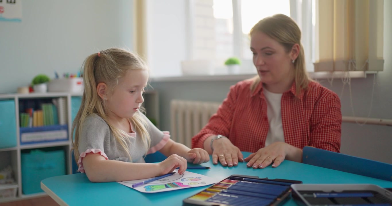 Kvinnelig lærer veileder ung jente under en tegnetime
