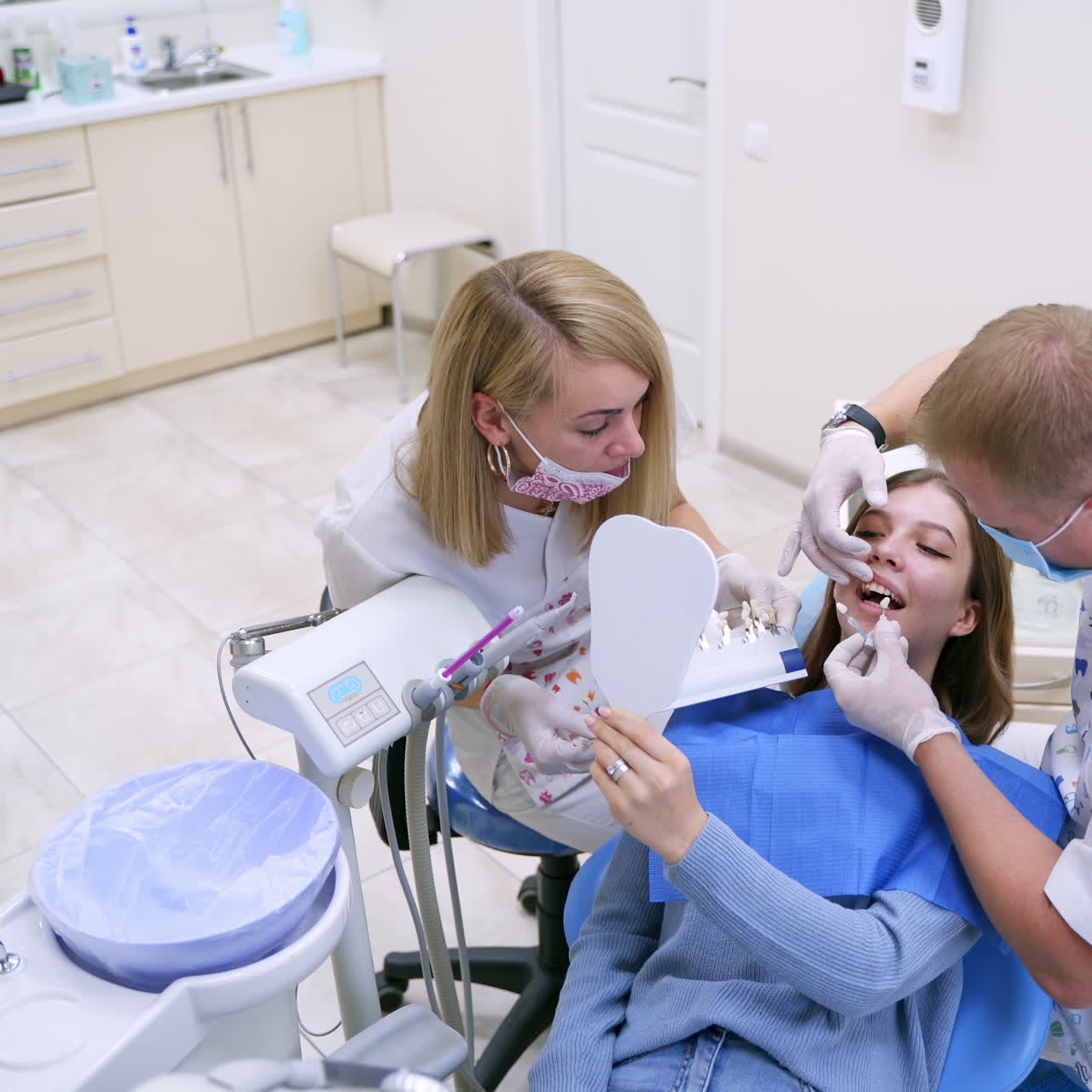 Dentistry concept. Assistant holds artificial teeth. Stomatologist selecting tooth implant for female patient in modern dentist office.