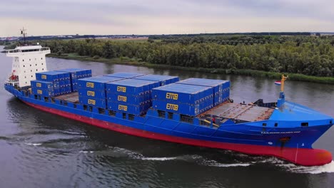 Impresionante-Toma-De-Un-Gran-Barco-Portacontenedores-Panda-Azul-Con-Viento-De-Cola-Navegando-En-El-Río-Oude-Maas,-Países-Bajos