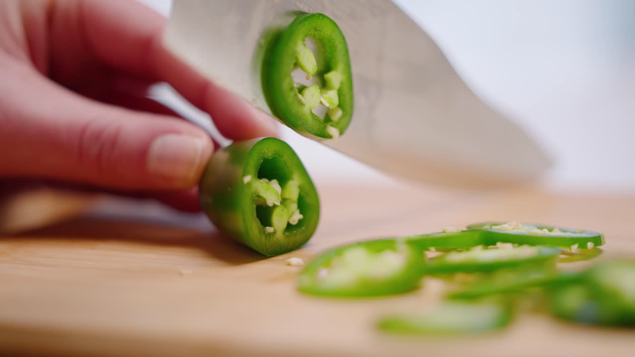 슬로우 모션으로 커팅 보드에 녹색 jalapeño 고추를 자르는 백인 손