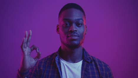 man with ok sign in a studio setting with colorful light