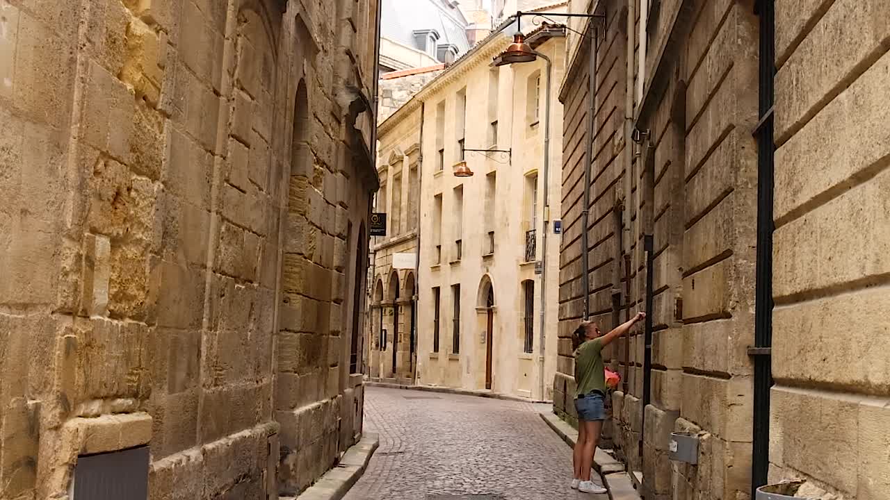 Una mujer explora una calle tranquila y estrecha bordeada de edificios y arquitectura históricos de piedra.