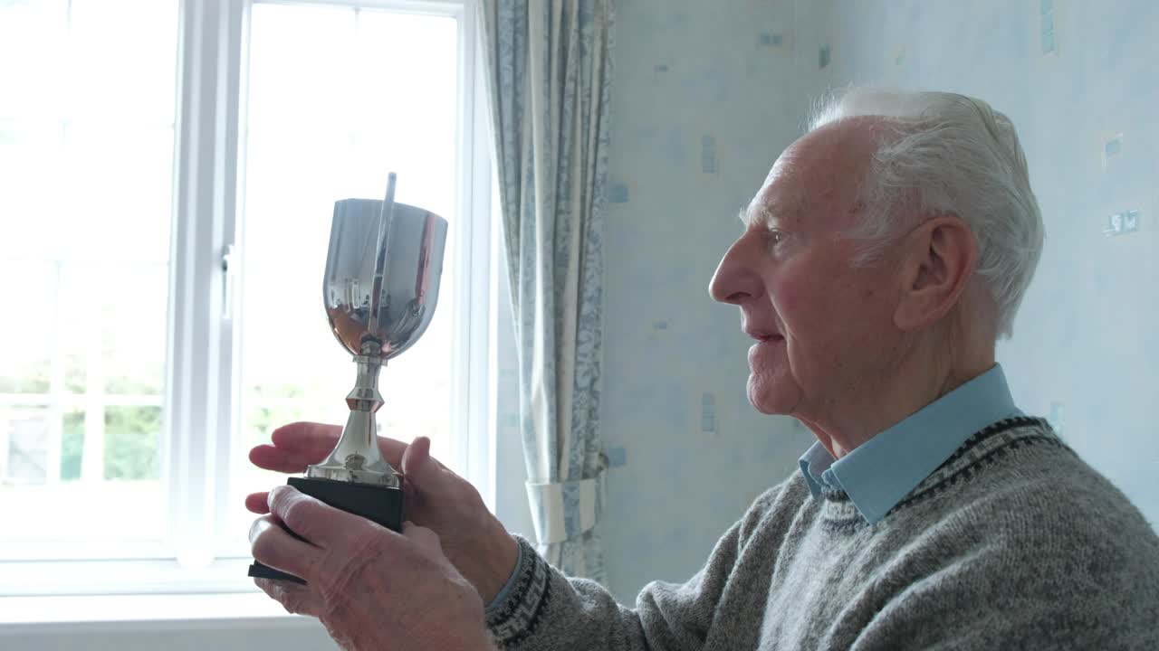 고위 백인 남자가 트로피를 점검하고 있습니다.