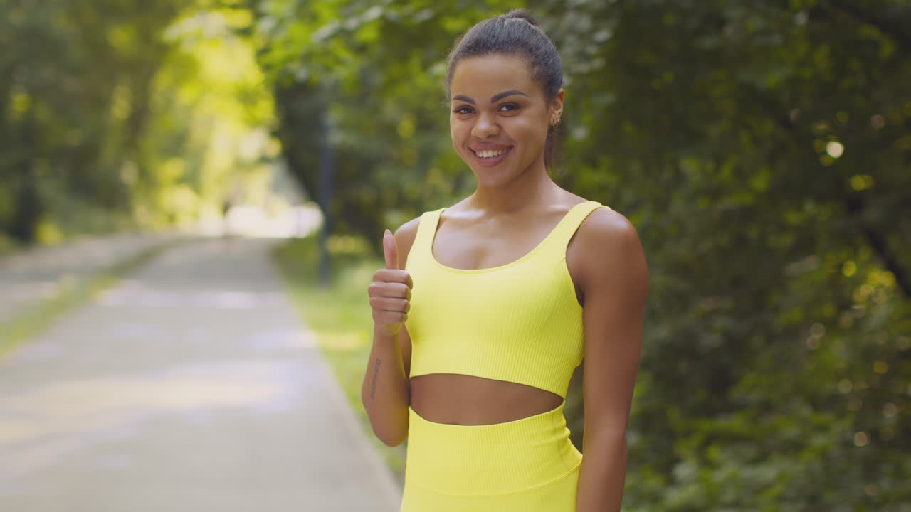 mujer en ropa deportiva dando pulgares hacia arriba