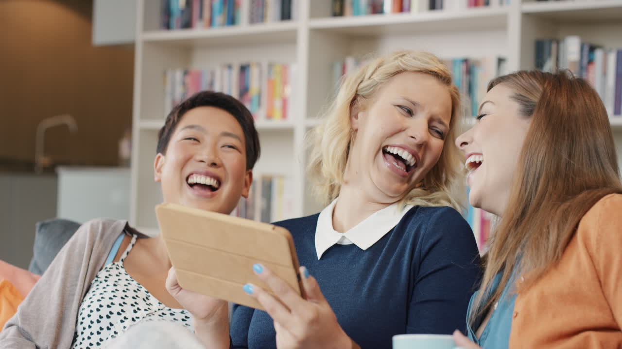 집에서 소셜 미디어를 위해 디지털 태블릿을 사용하는 친구들이 재미있게 웃고 있습니다.