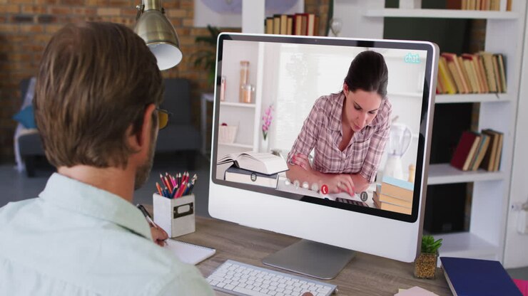Caucasian male teacher using computer on video call with female student