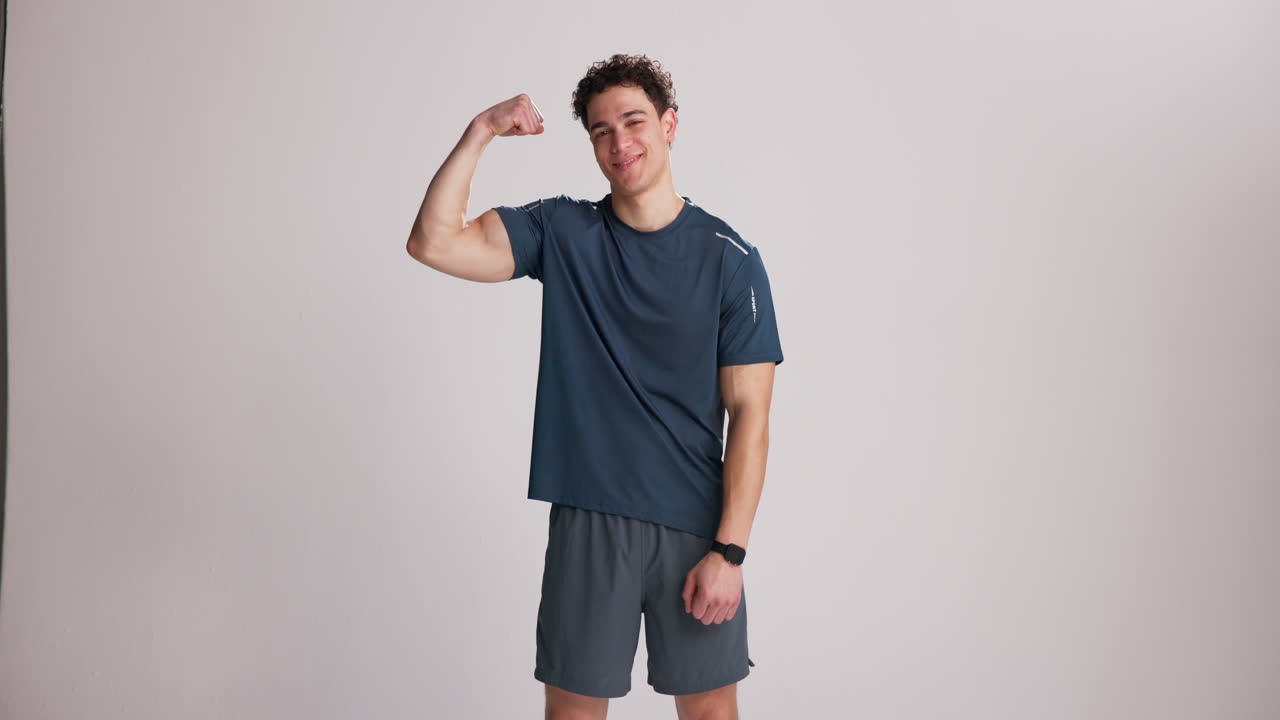 Young Man Flexing Bicep and Smiling at Camera