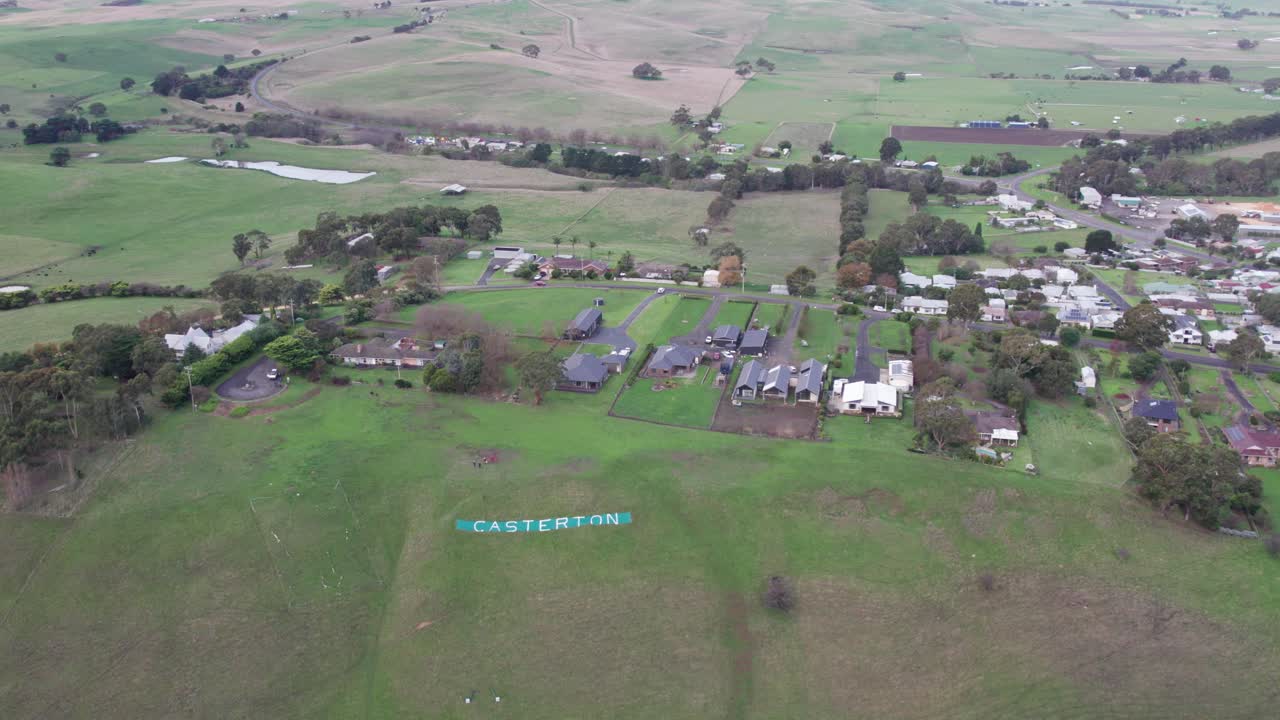 Reversing aerial view of the Casterton sign on the hill near the town. Casterton, western Victoria, Australia. June 2023.
