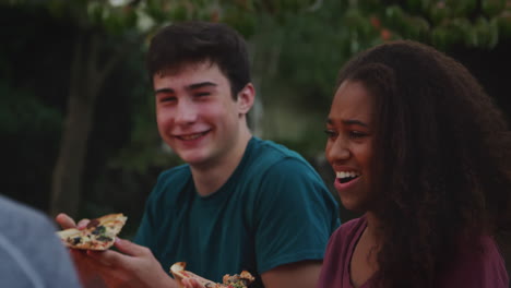 Teenage-friends-sit-round-a-firepit-eating-take-away-pizzas