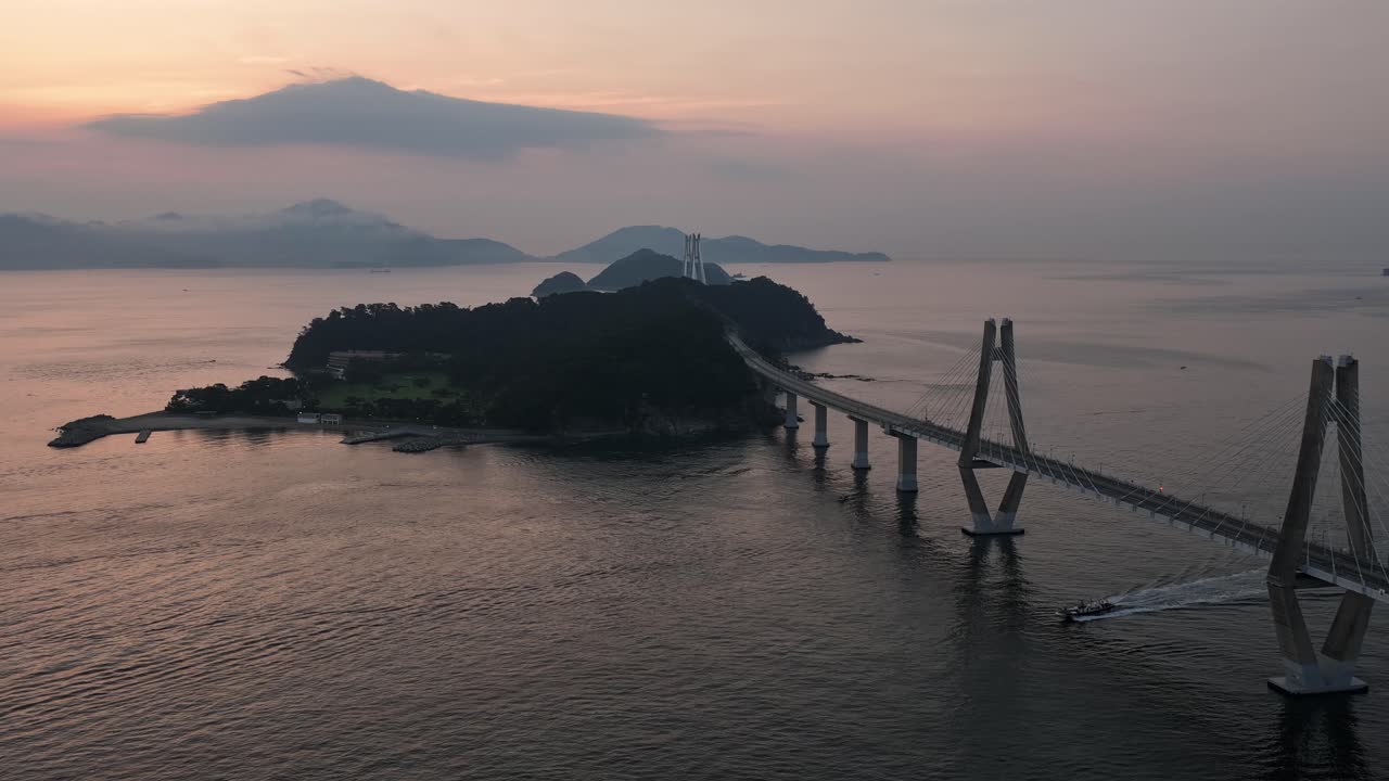 Drone circles a pylon of the scenic Geoga Bridge as boats sail on the water