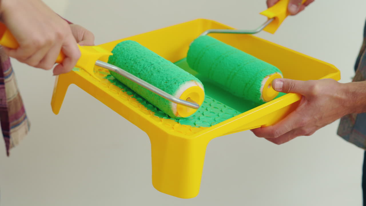 Painting a room with green paint using paint rollers