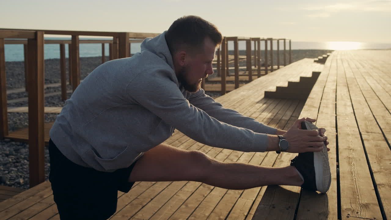 Man Stretching on a Beach Boardwalk at Sunrise/Sunset