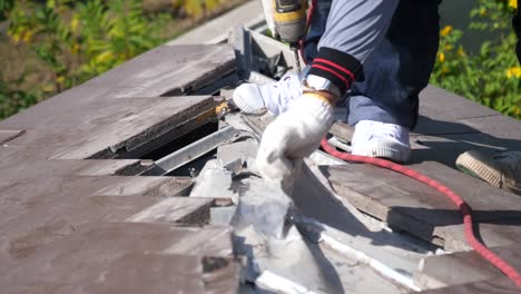 asian worker doing roof tiles installation, cutting, measuring process, close up