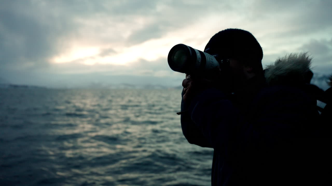 fotógrafo de viajes en un paseo en barco al atardecer en skjervoy, noruega. toma media, cámara lenta