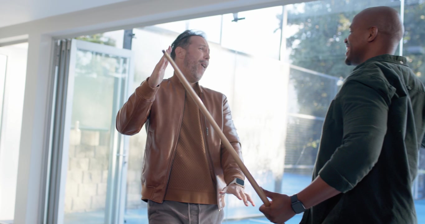 Diverse men around pool table watching man in pullover lining up, striking cue, cheering after shot