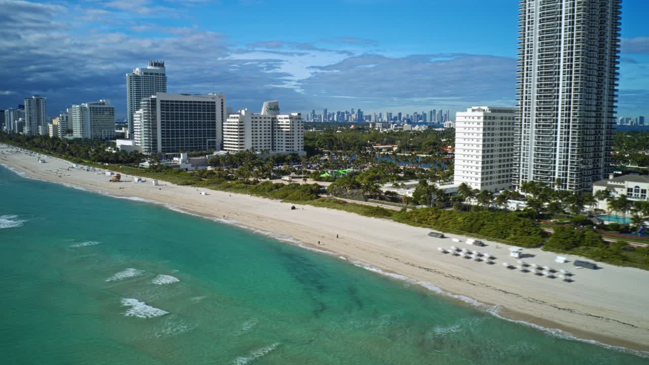 Oceanfront towers rise above the wide sandy shoreline of North Beach as turquoise Atlantic water meets Miami’s distant skyline, creating a dynamic coastal corridor along Florida’s southeast coast