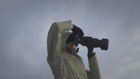 Woman-taking-photos-with-long-telephoto-lens-with-sky-cloud-background,-low-angle