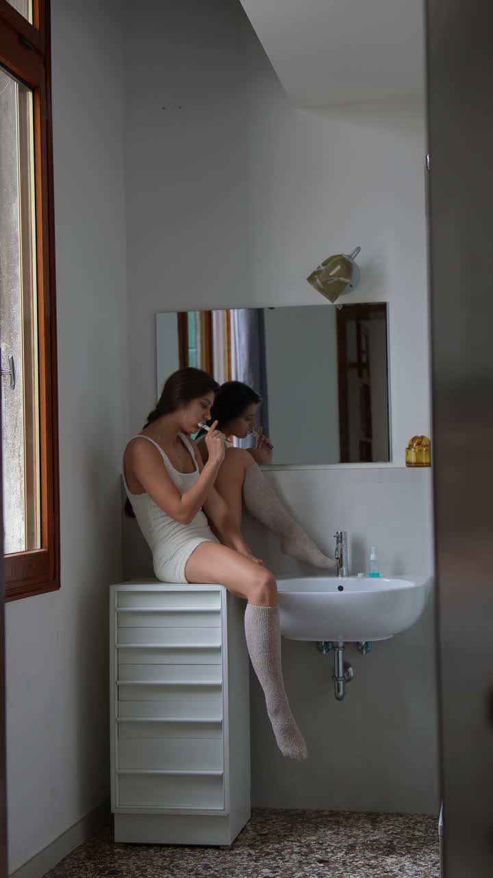 mujer cepillándose los dientes en un baño acogedor