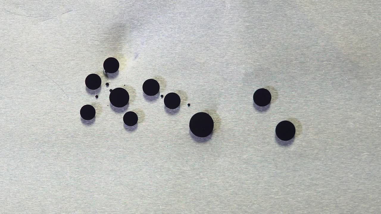черные точки чернил на металлической поверхности