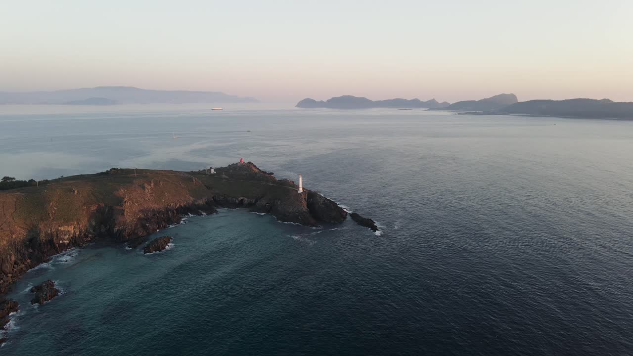 Filmato aereo con drone di un faro all'alba e onde dell'oceano che si infrangono sulle rocce
