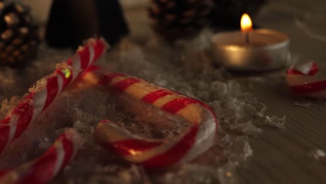 Candy-cane-love-heart-and-Christmas-decorations-in-warm-candle-scene-zoom-in-shot