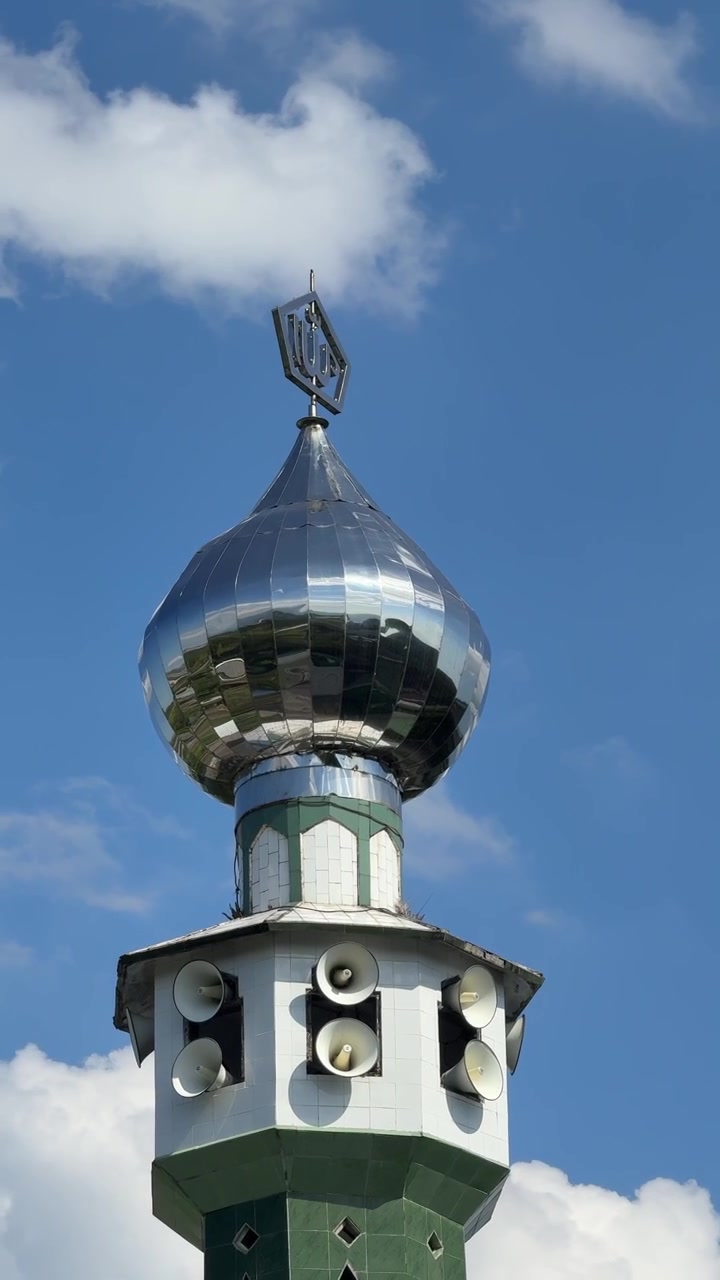 Glänzende Metallkuppel eines Moscheeminaretts vor blauem Himmel