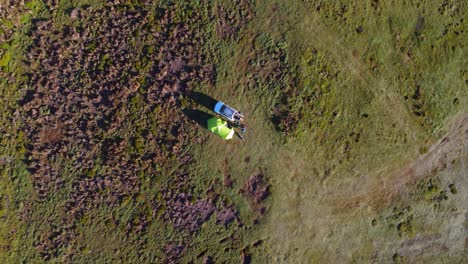 cinematic aerial dolly-out shot of a lone camping tent and vehicle in the middle of the vast ecuadorian paramo. as the drone pulls back, the isolation and immensity of the landscape become evident.