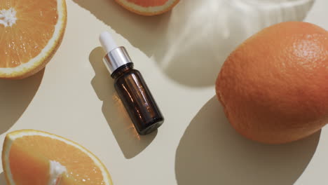 video of make up bottle with pipette, citrus slices and copy space on yellow background