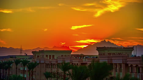 Time-lapse-shot-of-golden-sunset-behind-mountains-in-Africa-with-African-buildings-in-foreground