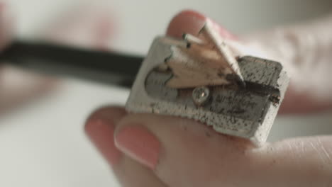 person sharpening a pencil in a metallic sharpener