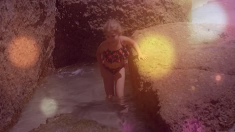 spots of light against caucasian girl walking close to the rocks near the sea