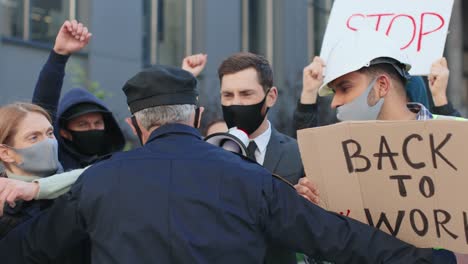 полицейский останавливает группу людей во время демонстрации против ковида 19 на улице